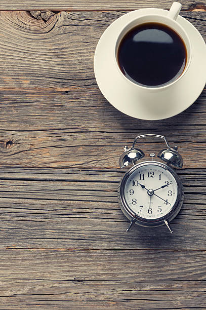 istock Clock and coffee on a wooden table. 483731102