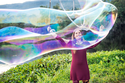 Woman making giant soap bubbles in a park.