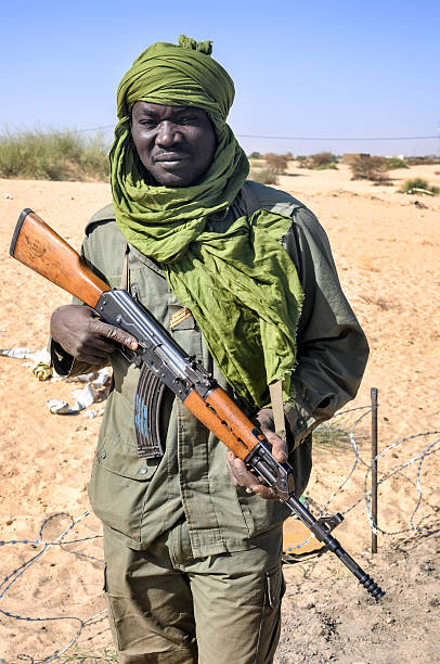 Malian military soldier Gao, Mali - February 14, 2013:  Malian soldier standing in borders surrounded by arid desert in Mali. He is guarding the area and holding the gun - Kalashnikov Ak-47. His face is tired and serious. Mali stock pictures, royalty-free photos & images