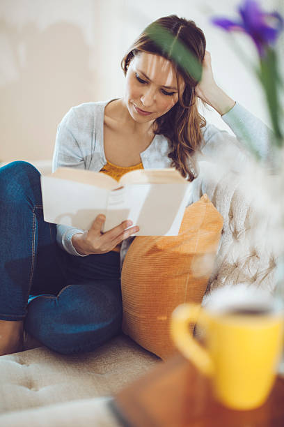 hermosa mujer latina leyendo un libro en su hogar - living room elegance women long hair fotografías e imágenes de stock