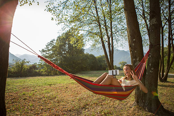 istock Woman on hammock taking selfie using phone on selfie stick 483735558