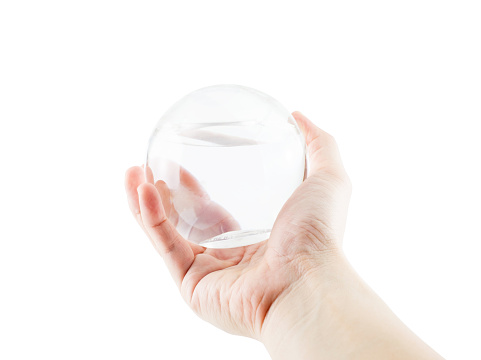 Hand holding round plastic glossy ball with water inside isolated on white background,Eco concept.