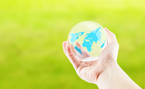 istock Hand holding round glossy ball with world map on green 483738814