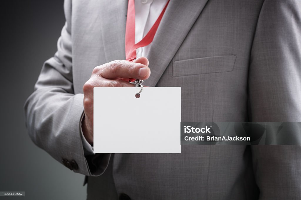Businessman holding blank ID badge Businessman at an exhibition or conference showing a blank security identity name card on a lanyard Security Pass Stock Photo