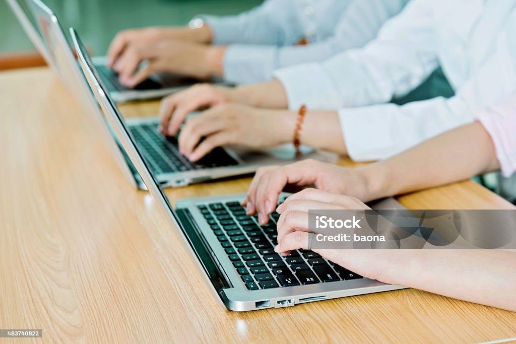 working on laptops Group of people hand working on laptops in a row. 2015 Stock Photo