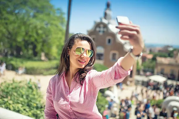 Photo of woman taking selfie with mobile phone and posting, social media.