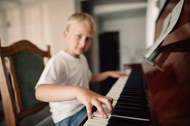 istock little happy boy plays piano 483743946