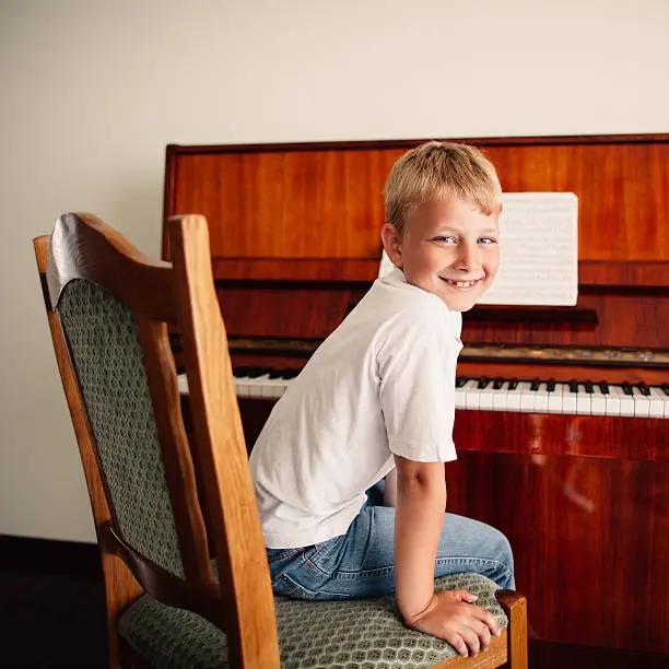 little happy boy plays piano at home