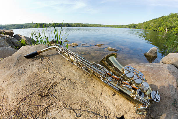 Summer Jazz saxophone in nature lying on rocks lakeside