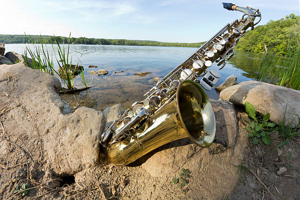 Summer Jazz saxophone in nature lying on rocks lakeside