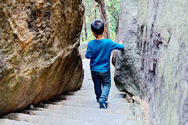 Little boy walking down stairs outdoors.