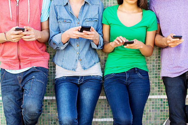 istock Teenage Friends Using Smart Phone While Leaning On Wall 483752831