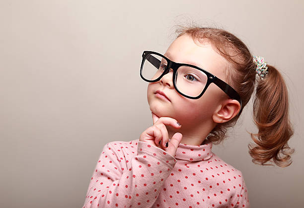 istock Cute kid girl in glasses thinking and looking serious 483754521