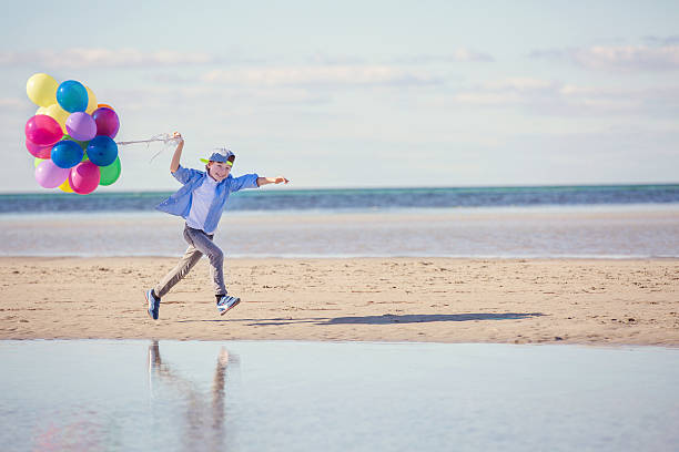istock Happy boy plays with colored balloons on the beach 483766390
