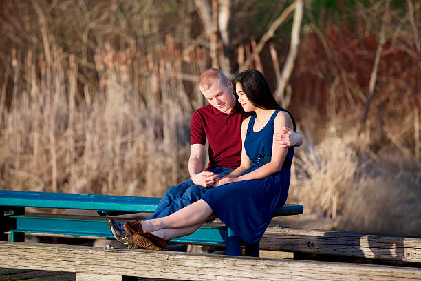 Young interracial couple praying together on wooden pier stock photo