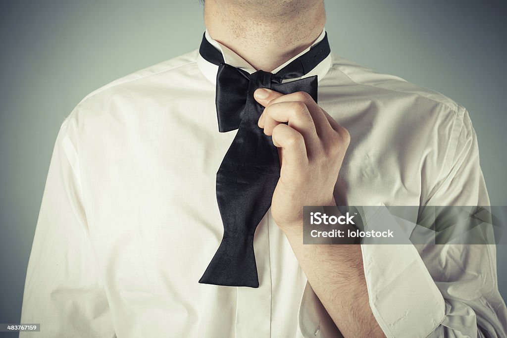 Young man tying a bow tie Young man is showing how to tie a formal bow tie Adult Stock Photo
