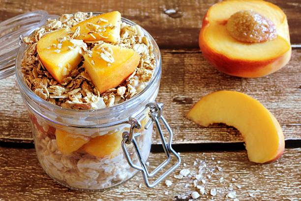 übernachtung haferflocken und müsli mit pfirsichen auf rustikal holz - jar oatmeal granola glass stock-fotos und bilder