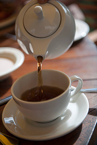 istock Teapot pouring tea into cup and saucer 483767679