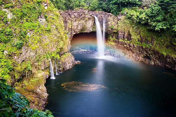 Beautiful Rainbow Falls in Hilo Hawaii forms cascading flows into a natural pool and often casts colorful rainbows when the sun position is just right, as shown here.