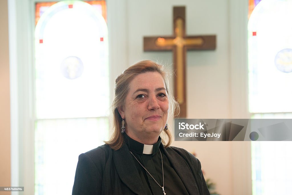 Candid of Female Minister Inside Church Candid of real female pastor inside church with cross in background. Priest Stock Photo