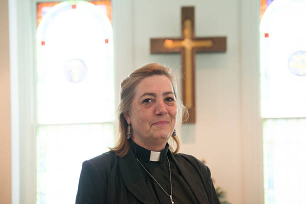 Candid of Female Minister Inside Church Candid of real female pastor inside church with cross in background. protestantism photos stock pictures, royalty-free photos & images