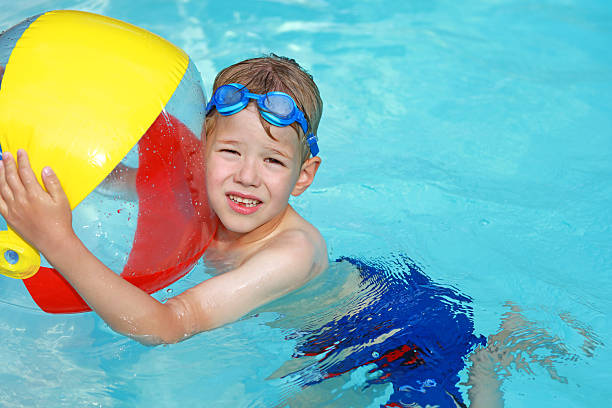 enfant avec ballon de plage coloré nager dans la piscine - beach ball swimming pool ball child photos et images de collection