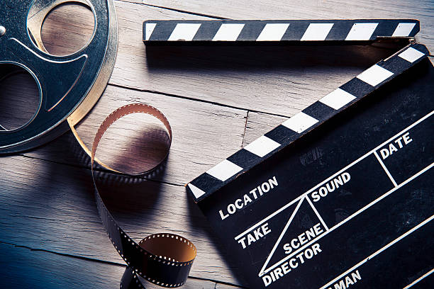 Film reel and movie clapper on wooden background stock photo