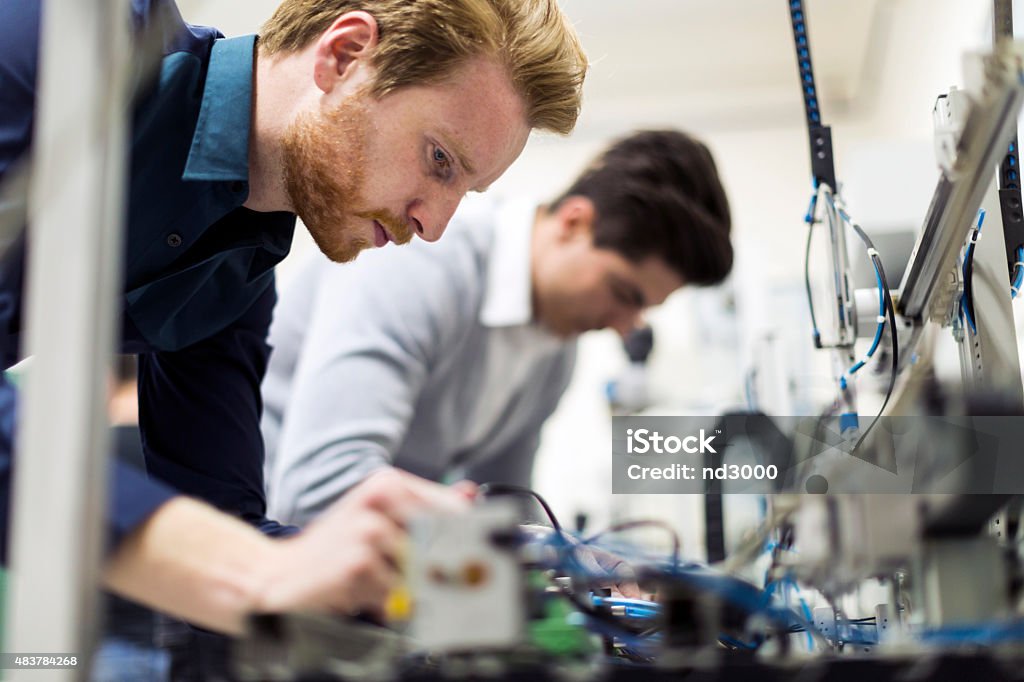 Dos joven atractivo los ingenieros trabajando en componentes de electrónica - Foto de stock de Ingeniero libre de derechos