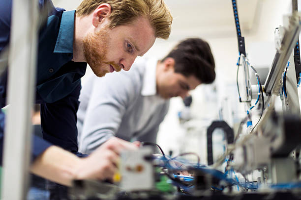 two young handsome engineers working on electronics components - elektronikindustri bildbanksfoton och bilder