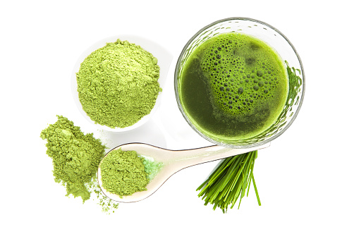 Green food supplement. Spirulina, chlorella and wheatgrass. Green pills, wheatgrass blades and ground powder isolated on white background, top view. Healthy lifestyle..
