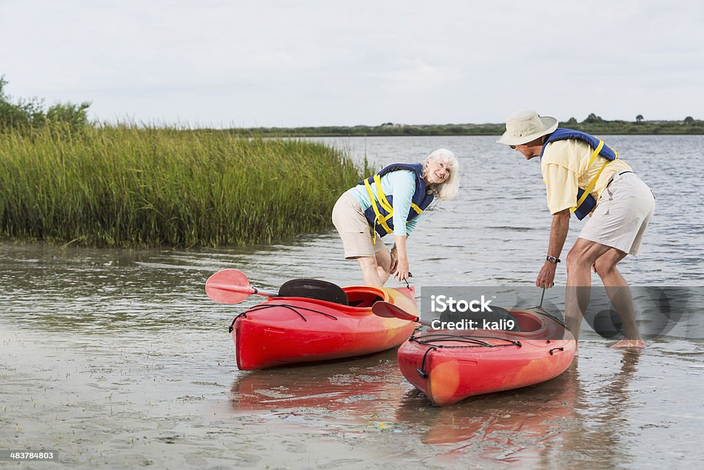Senior couple putting kayaks into water Active senior couple at water's edge, pulling kayaks into water - Intracoastal waterway, Florida. Kayaking Stock Photo