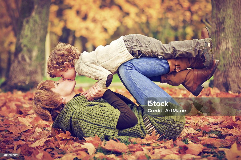 Mother and son in autumn Mother and 3 years old son in autumn park with maple leaves Leaf Stock Photo