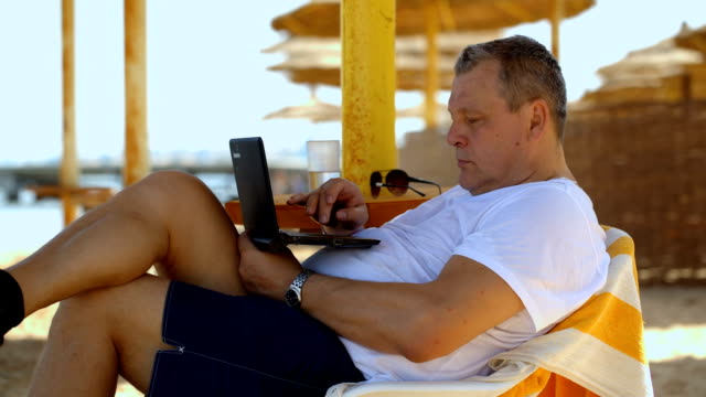Man relaxing with a laptop at beach resort