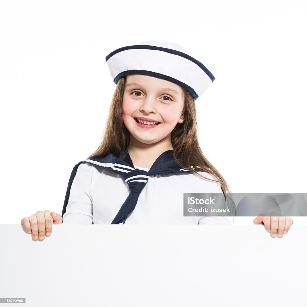 Happy sailor girl holding whiteboard Portrait of little girl dressed as a sailor holding whiteboard in hands and smiling at the camera. Studio shot, isolated on white. 2015 Stock Photo