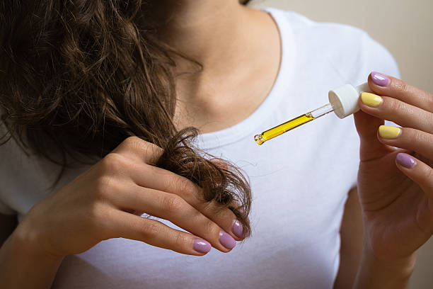 istock Young girl caring for curly hair tips using a  oil 483793858