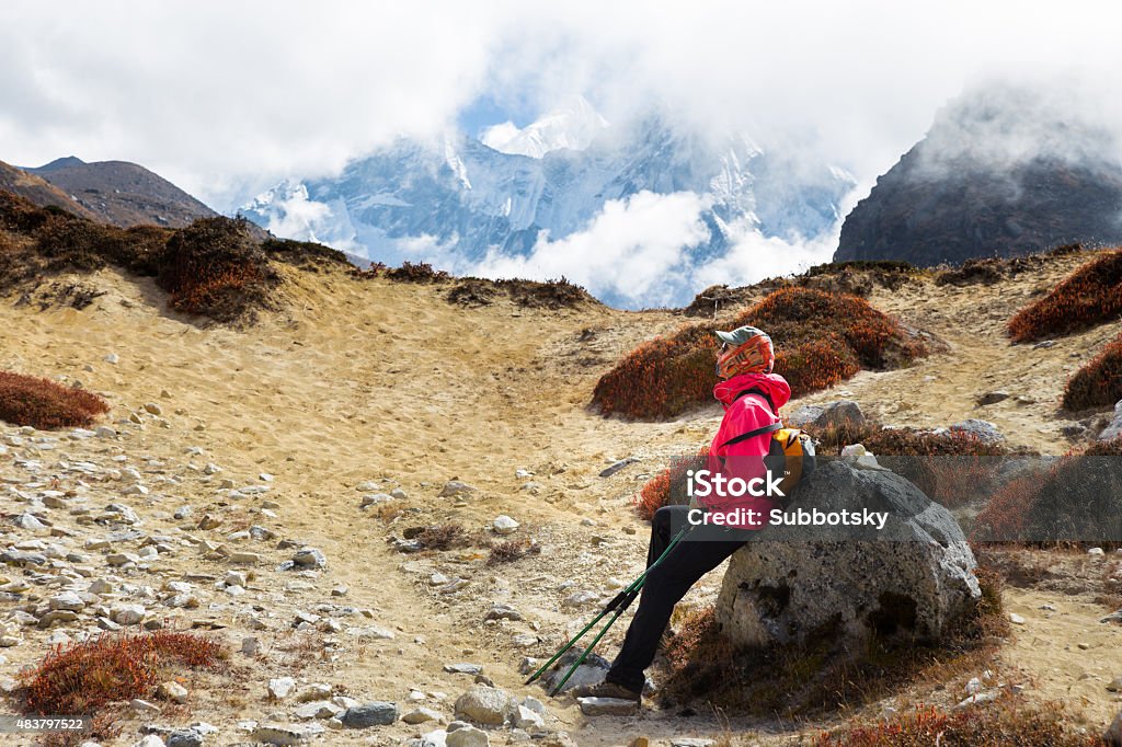 Woman tourist backpacker resting rock Ama Dablam mountain trail. Woman backpacker tourist resting stone, Ama Dablam snow peak base camp trekking trail route. Nepal traveling tourism. 2015 Stock Photo