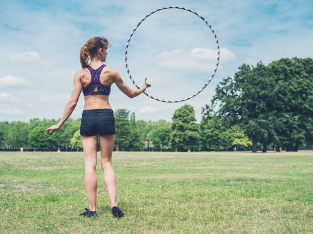 istock Woman twirling hula hoop in park 483800074