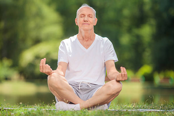 istock Senior man meditating seated on a blanket in a park 483807224