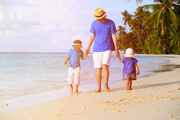 istock father and two kids walking on tropical beach 483809548