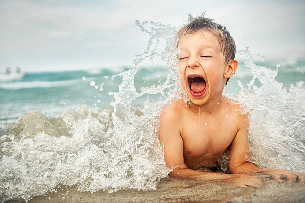 Little boy on a beach Portrait of a happy little boy splashed by wave on the beach. kid waves stock pictures, royalty-free photos & images