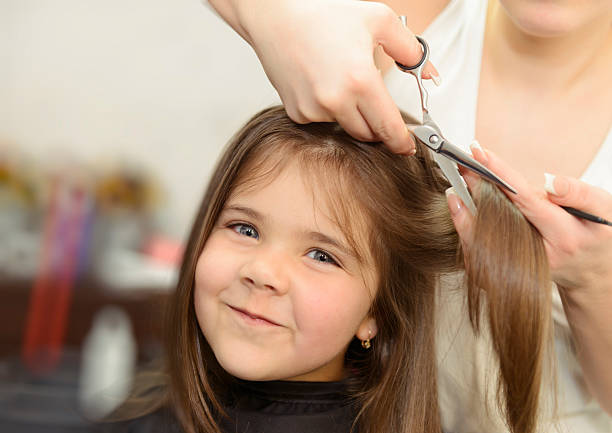 happy girl cutting hair little happy girl at hairsalon cutting her hair. cutting hair photos stock pictures, royalty-free photos & images