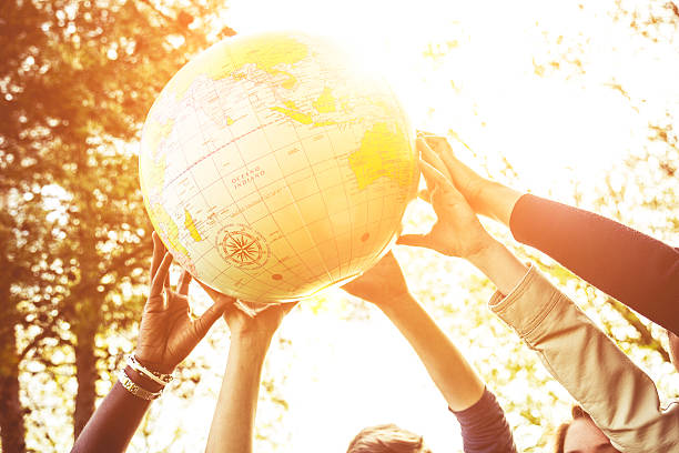 grupo de adolescentes sostiene un globo de tierra - adolescence teenager globe map fotografías e imágenes de stock