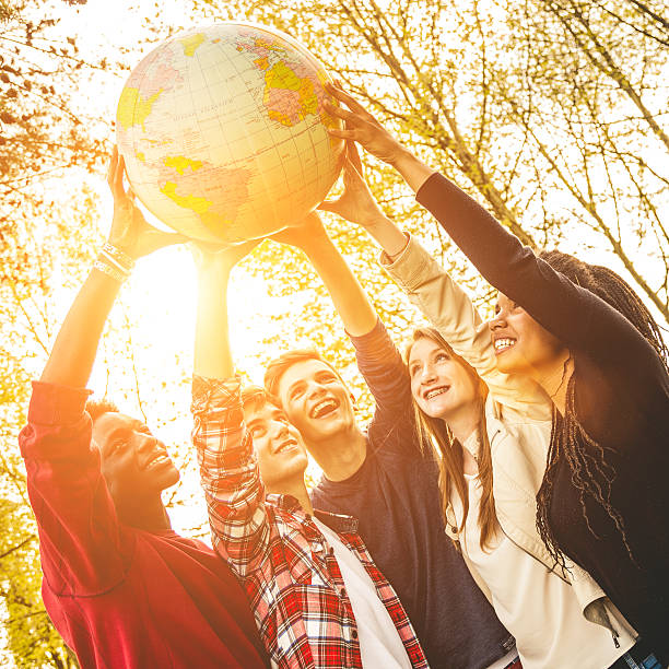 grupo de adolescentes sostiene un globo de tierra - adolescence teenager globe map fotografías e imágenes de stock