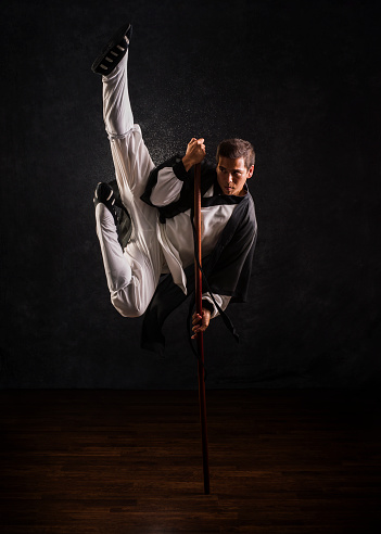 Stock photo of a Kung Fu Master in traditional dress performing a pole kick.