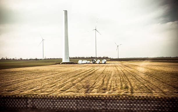 Wind turbine being built in  filed along a road. Terto vintage look