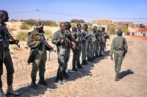Bamako, Mail- February 14, 2013: The photo speak about group of african soldiers in Mali who are standing with Kalashnikov in front of them commander during warm afternoon. All men wearing military uniform - camouflage clothes. The climate is arid and very tropical.