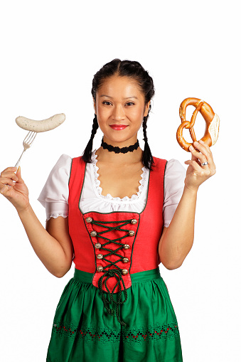 Asian woman wearing Dirndl holding pretze and veal sausage