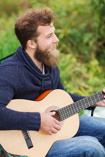 istock smiling man playing guitar in camping 483831644