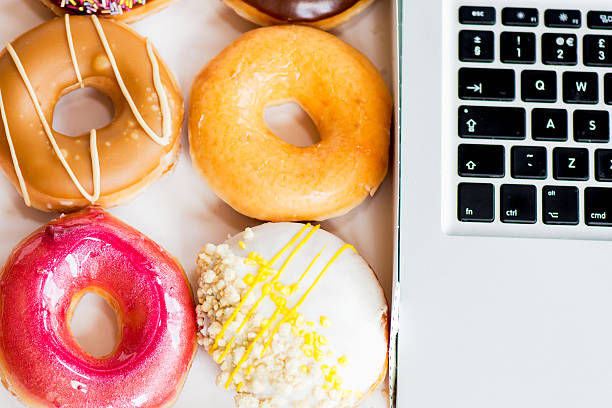 istock Snack from Glazed Doughnuts near Laptop on Working Desk 483833824