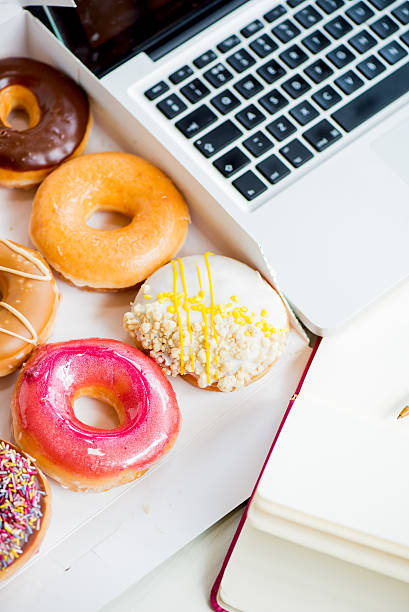istock Snack from Glazed Doughnuts near Laptop on Working Desk 483834078